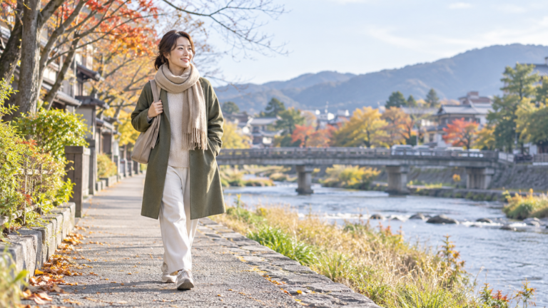 寒い季節に防寒して京都を思わせる川沿いを歩く女性のイメージ